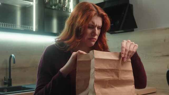 Unhappy Caucasian woman unpacking fast food order delivery sniffing bad smell sniff smelling unpleasant odor disgusting open meal paper bag female client girl feeling nauseous stink disgust at home