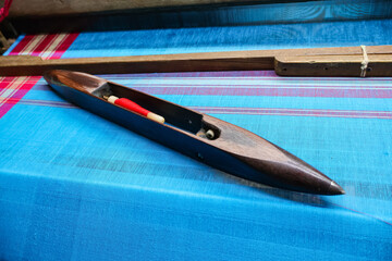 Weaving shuttle on a blue cotton saree. Traditional handloom accessory.