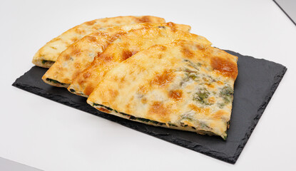 Georgian Khachapuri Pkhlovana With Herbs and Melted Cheese On White Surface