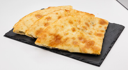 Georgian Khachapuri Pkhlovana With Herbs and Melted Cheese On White Surface
