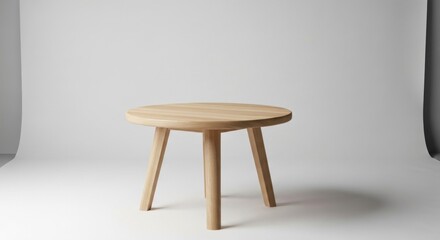 Simple, light wooden stool with round top and three legs on white backdrop