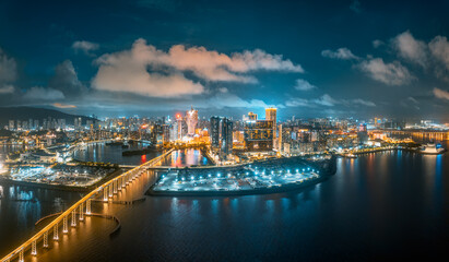Fototapeta premium Aerial view of a brightly lit city island featuring modern hotel buildings and a connecting bridge in Macau.