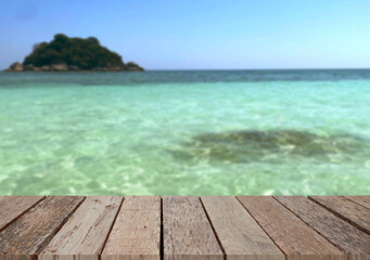 Fototapeta premium Wooden table top on the beach or sea.Party on the beach sunshine time concept.For montage product display or design key visual layout.View of copy space.