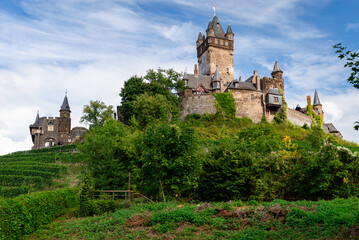 Cochem, Germany - September 9, 2025: The imposing central tower and stone walls of Reichsburg Cochem castle, a stunning example of medieval and Neo-Gothic architecture, rise above the green hillside.