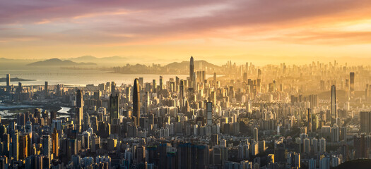 Breathtaking aerial cityscape of a dense modern metropolis with countless skyscrapers glowing under the golden light at sunset.