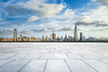 Empty stone tile square floor with a modern city skyline on a bright sunny day.