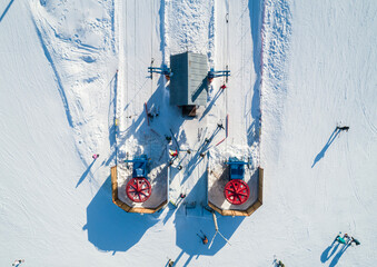 Skiers and snowboarders preparing to ascend the slopes at a winter resort in a snow-covered...
