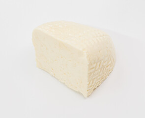 A pale block of cheese with a soft, textured rind sits on a bright white surface