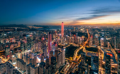 Aerial view of the modern city skyline with illuminated commercial buildings and urban traffic at dusk in Shenzhen.