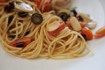Delicious spaghetti with olives and tomatoes on a plate, showcasing a flavorful meal