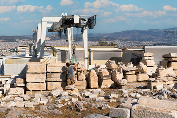 Restoration work on the acropolis of Athens with a worker operating a gantry crane among stacked...