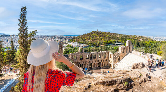 Young female tourist overlooking the ancient odeon of herodes atticus and lycabettus hill from the acropolis in Athens, Greece