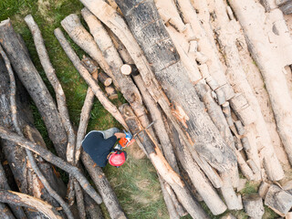 Lumberjack with a chainsaw cutting trees in the forest. Preparing firewood for winter. Top down view. Aerial view from drone
