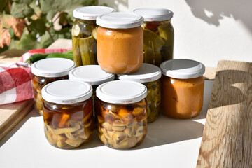 large number of cans with various preserves — mushrooms, squash caviar, and cucumbers, top view
