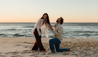 Man proposing to woman at sunset on a sandy beach