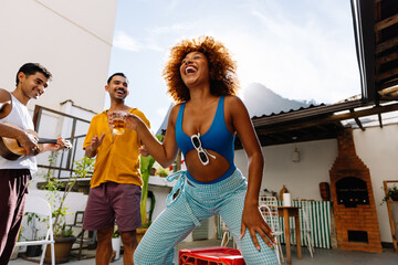 Group of friends enjoying music and drinks on a sunny rooftop