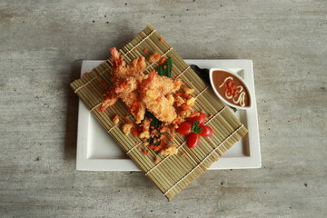 Exquisite Tempura Dish Displayed on a Wooden Mat with Dipping Sauce