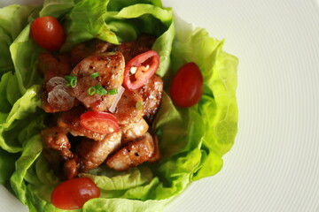 Delicious pork with fresh lettuce, cherry tomatoes, and red chili pepper arranged artistically