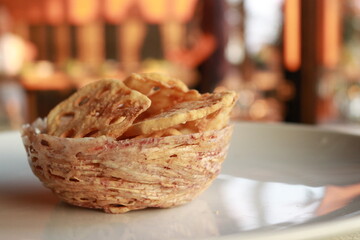 Delicious taro chips presented in an intricately woven basket on a plate, ready to be enjoyed