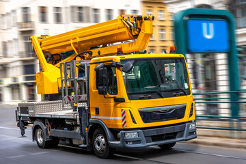 Yellow utility truck with hydraulic lift. Urban infrastructure.