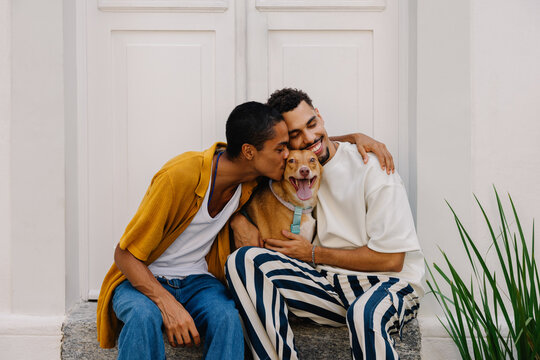 Happy couple embracing their smiling dog on a bright sunny day - Powered by Adobe