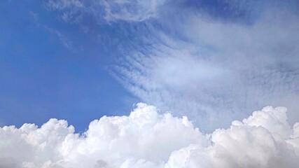 Photo of the sky filled with billowing white cumulus clouds rising majestically into a serene...
