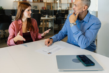HR male recruiter talking with young female applicant during job interview at modern office....