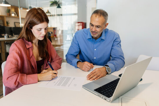 Young woman signing a job contract with human resources manager during an interview meeting at the office. Employment, hiring, and professional agreement concept - Powered by Adobe