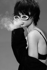 Black and white portrait of a stylish woman smoking with sunglasses and edgy haircut
