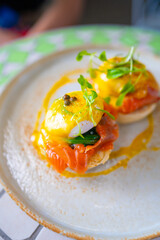 Closeup gourmet eggs benedict with salmon and greens