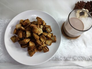 view of bread caramel popcorn on a white plate with a glass of milk on a white tablecloth