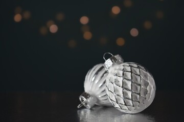 Close-up of round silver shiny Christmas tree balls against a backdrop of glowing garland