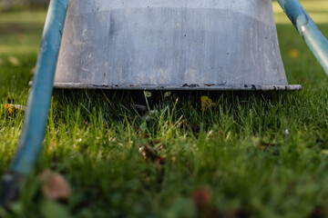 black cat with a white neck is hiding under a metal wheelbarrow that has been turned upside down in...