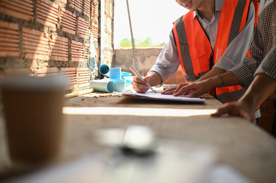 Close-up of a house owner reviewing and documenting progress with the contractor at a housing project