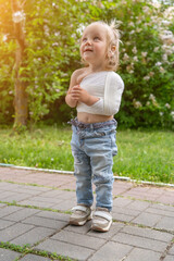Fototapeta premium Adorable toddler with bandaged arm and chest standing outdoors on sunny day, looking up with curious and hopeful expression, symbolizing childhood resilience and recovery