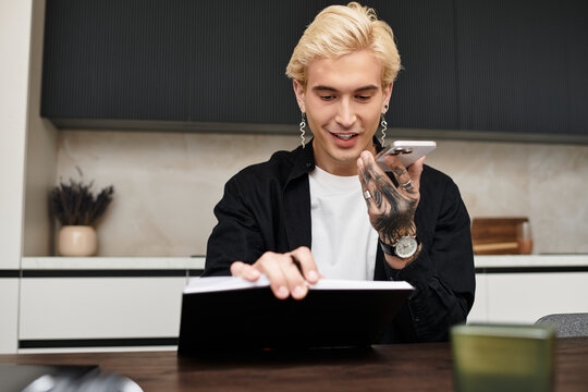 Young handsome man in a modern apartment engaging on a phone call while reviewing documents