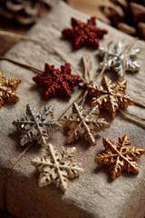 Fototapeta premium A collection of generic small, decorative ornaments (stars, snowflakes) scattered on the top of a beautifully wrapped gift.