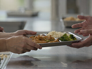 Two Hands Pass Plate Of Roast Turkey And Steamed Broccoli In Kitchen Setting. Two hands pass a plate of roasted turkey and broccoli in a warm kitchen, capturing sharing, home cooking, and family.