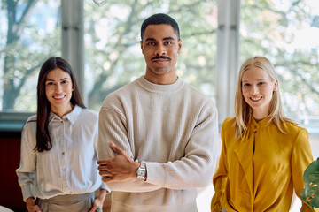 Naklejka premium Diverse co-workers smiling at camera, showing teamwork, confidence, and professionalism in a contemporary office setting