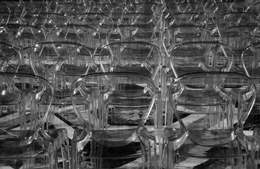 A row of clear plastic chairs. Black and white photo.