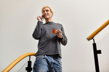 Young man enjoying a casual conversation while holding a cup in a stylish apartment setting