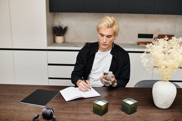 Young man reflecting on dreams in a stylish modern apartment while writing in a journal
