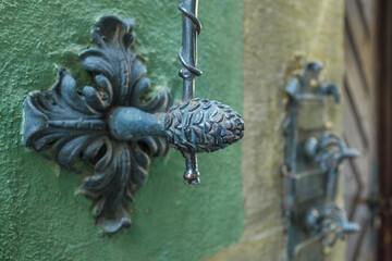 Historischer Glockenzug aus Eisen mit Zugstab vor grüner Wand und unscharfen Klingelschildern und Holztüre in der Altstadt von Esslingen am Neckar