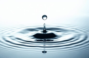 A close-up of a water droplet creating ripples on a smooth surface