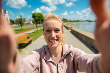 Fototapeta premium Woman smiling taking selfie after exercising outdoors
