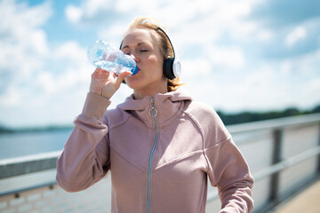 Woman runner hydrating with water bottle outdoors