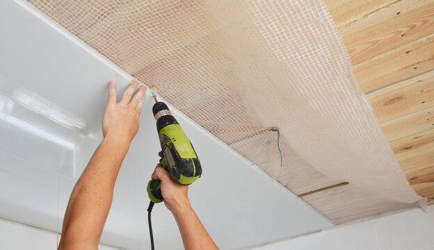 PVC Ceiling Panels, cladding installation indoors. Builder installing, repair white PVC Ceiling Boards in the house bathroom during renovation