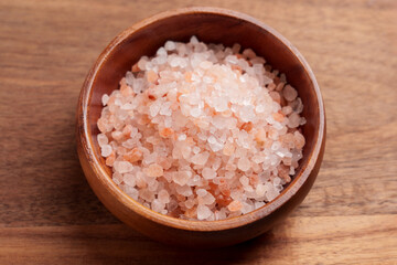 Coarse Himalayan salt with orange and white crystals in wooden bowl