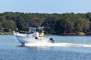 Fishermen on center console fishing boat enjoy summer day on the lake. Power boat cruising on...