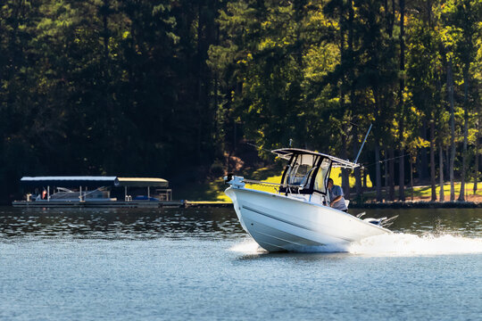 Fisherman on center console fishing boat enjoy summer day on the lake. Power boat cruising on freshwater lake.